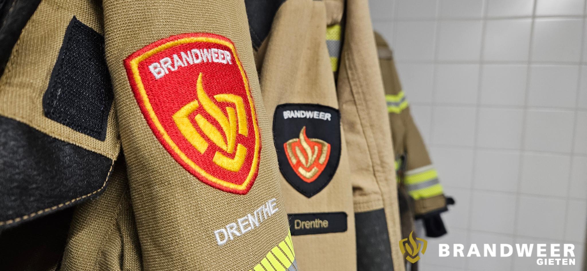 Brandweeremblemen op de mouwen van hangende uitrukjassen.